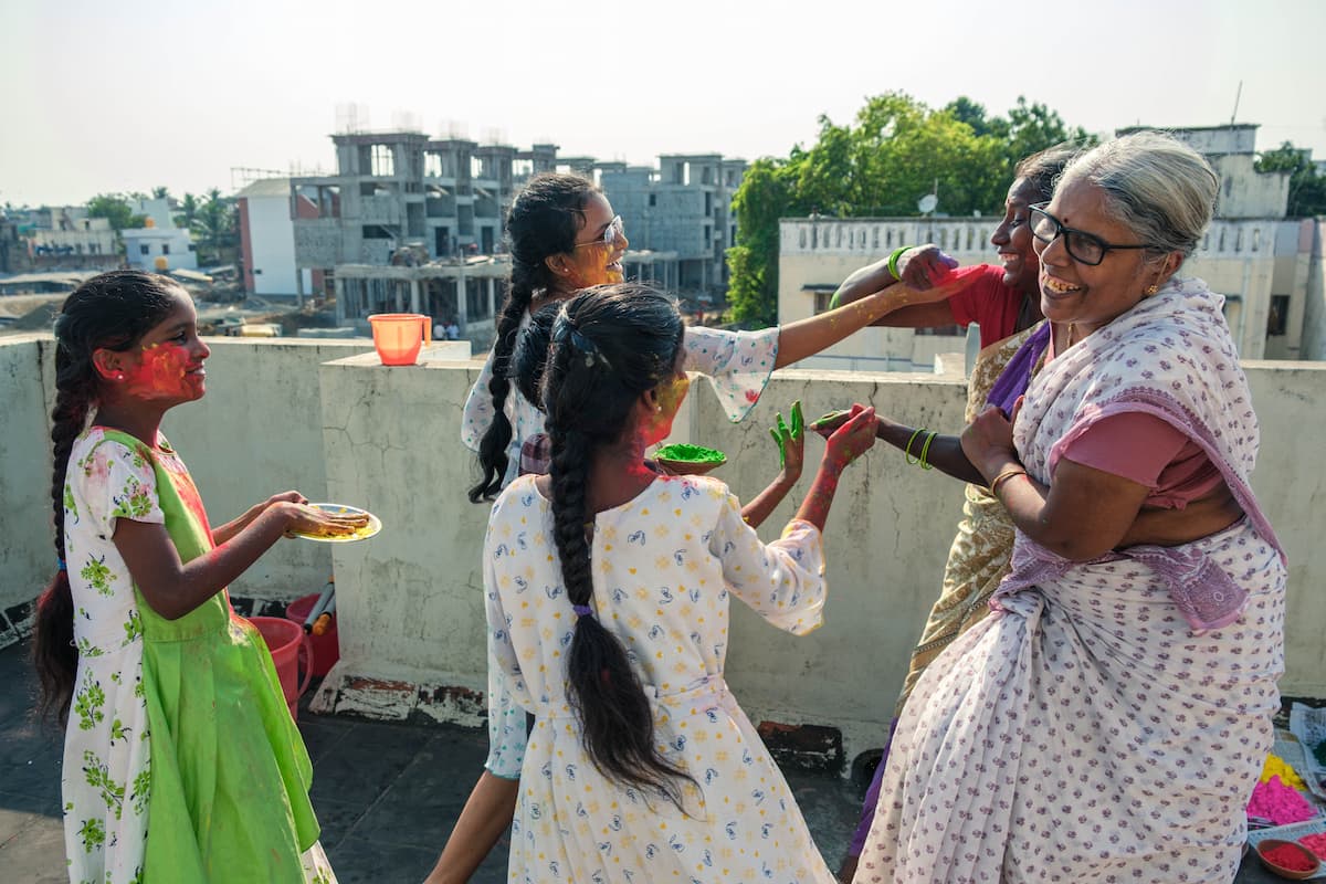 A group of kids playing holi with colours and water on the terrace under evening sunlight